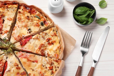 Tasty quiche with tomatoes and cheese served on white wooden table, above view