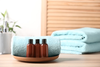 Photo of Mini bottles with cosmetic products and towels on table, space for text. Hotel amenities