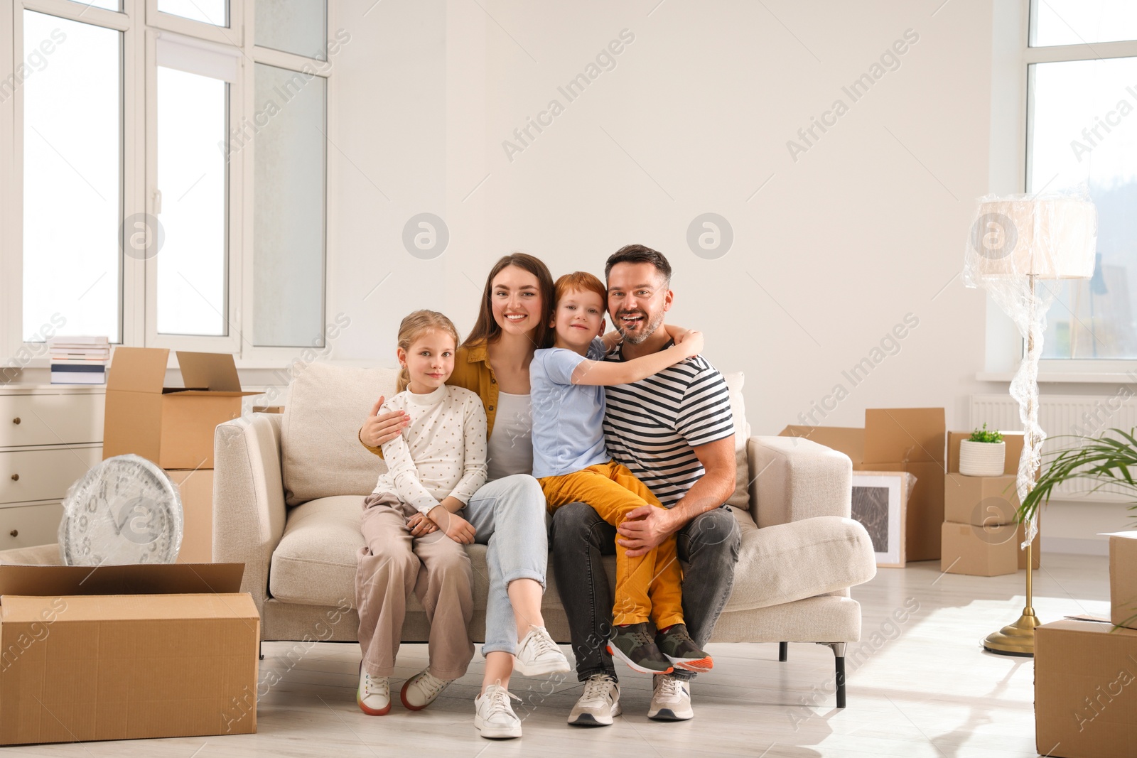 Photo of Happy family sitting on couch in new apartment. Moving day