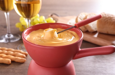 Pot with delicious cheese fondue and bread on table