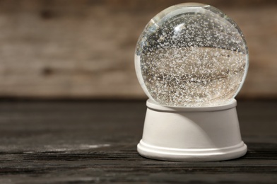 Photo of Magical empty snow globe on wooden table. Space for text