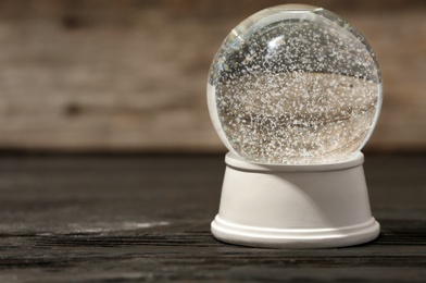 Magical empty snow globe on wooden table. Space for text