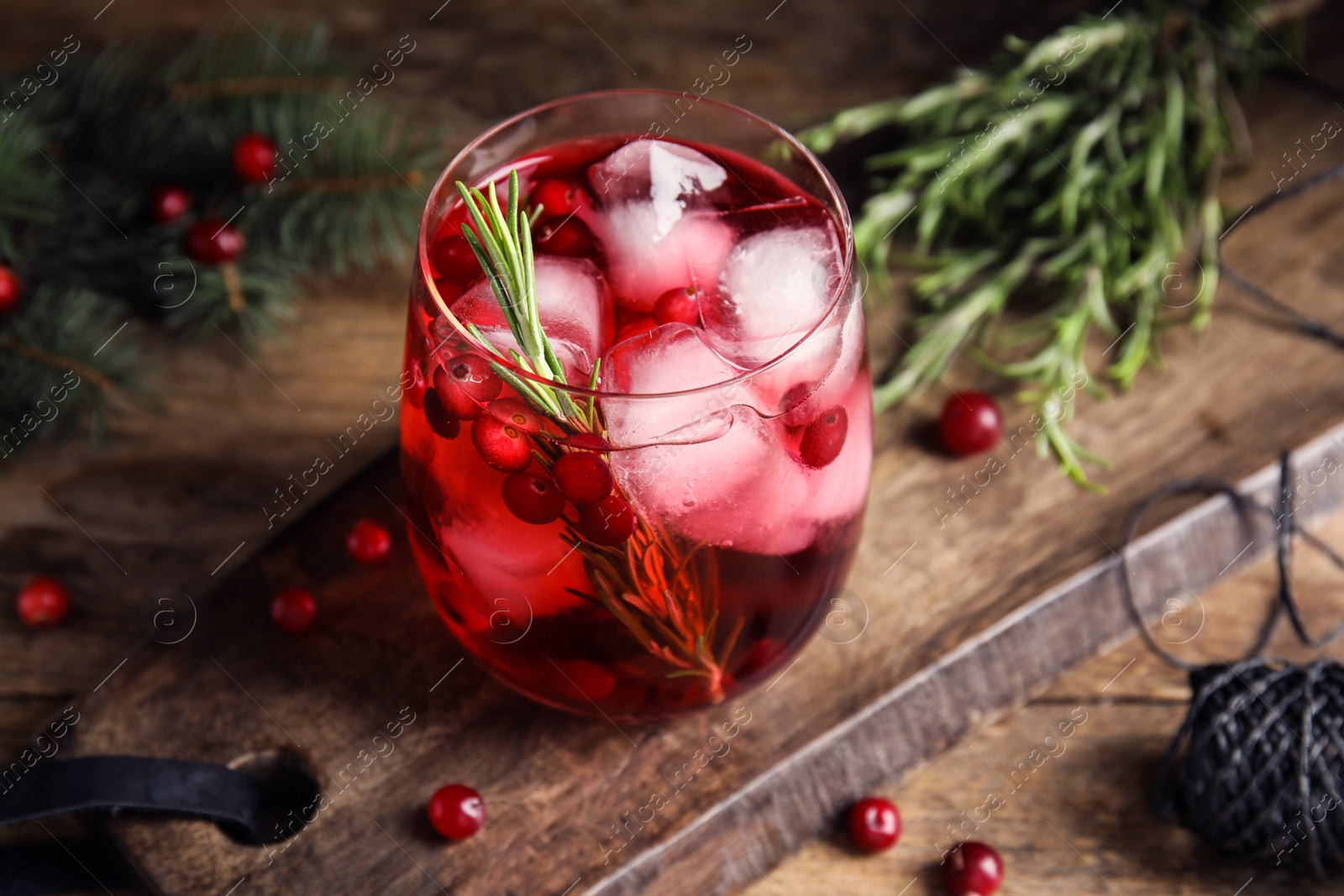 Photo of Tasty refreshing cranberry cocktail with rosemary on wooden table, closeup