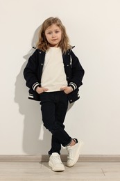 Fashion concept. Stylish girl posing near white wall