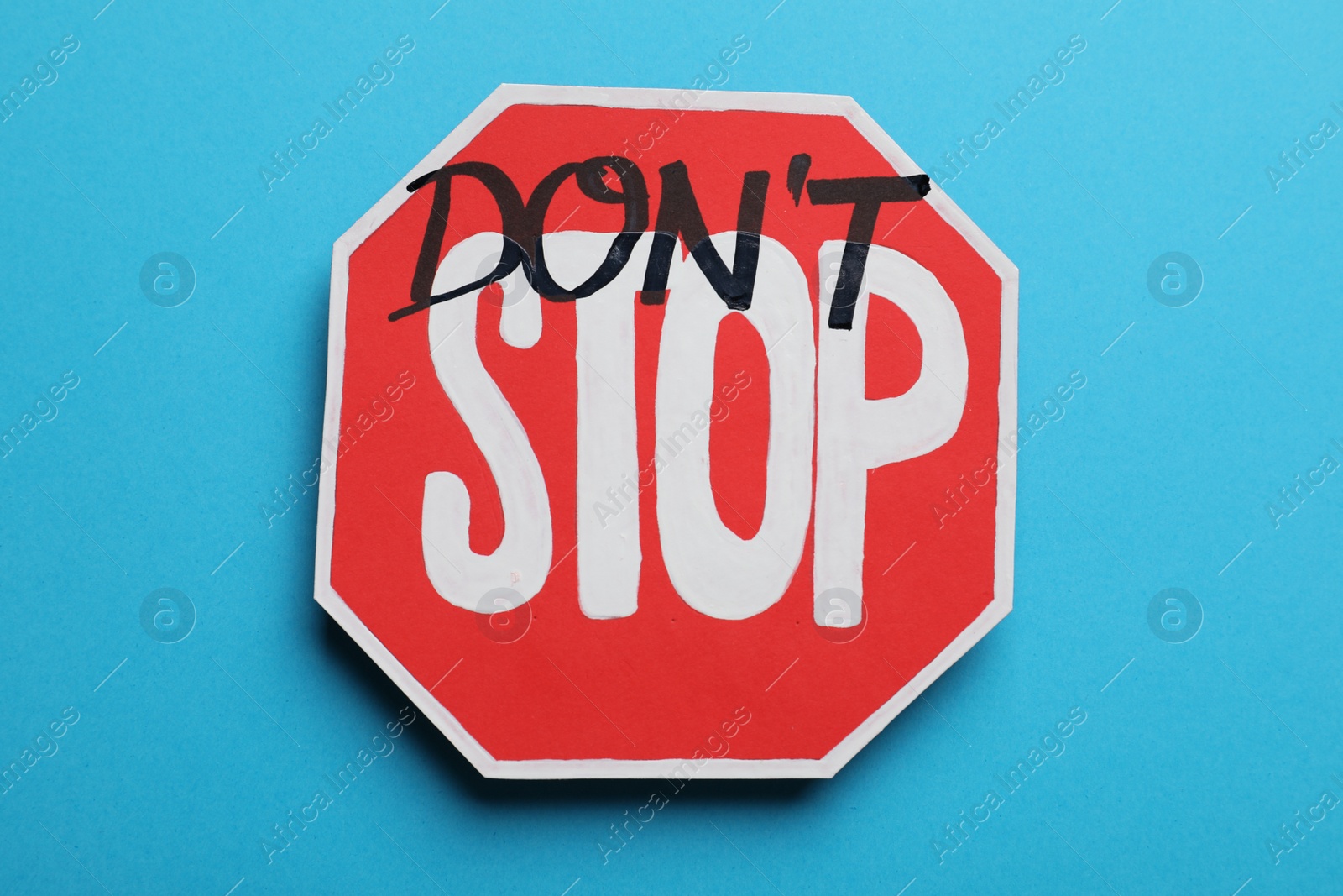 Photo of Don't stop - motivational phrase. Road sign sticker with added written text on light blue background