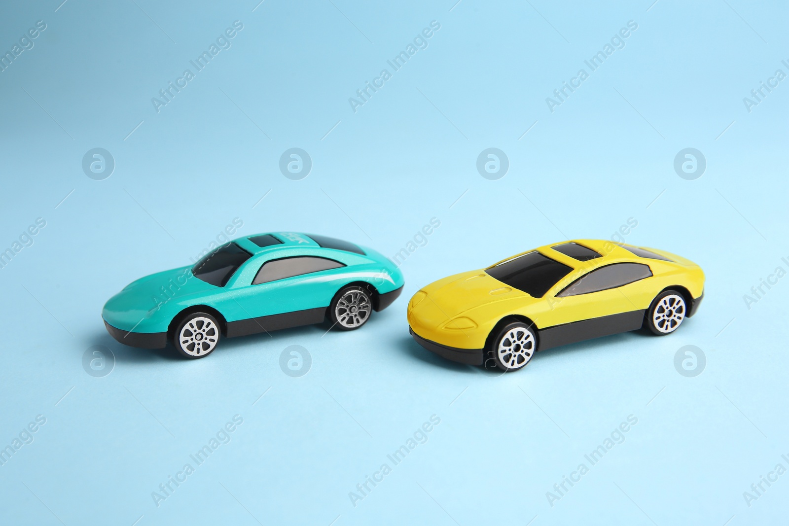 Photo of Two bright cars on light blue background. Children`s toys