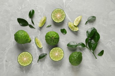 Photo of Fresh ripe bergamot fruits with green leaves on light grey marble table, flat lay