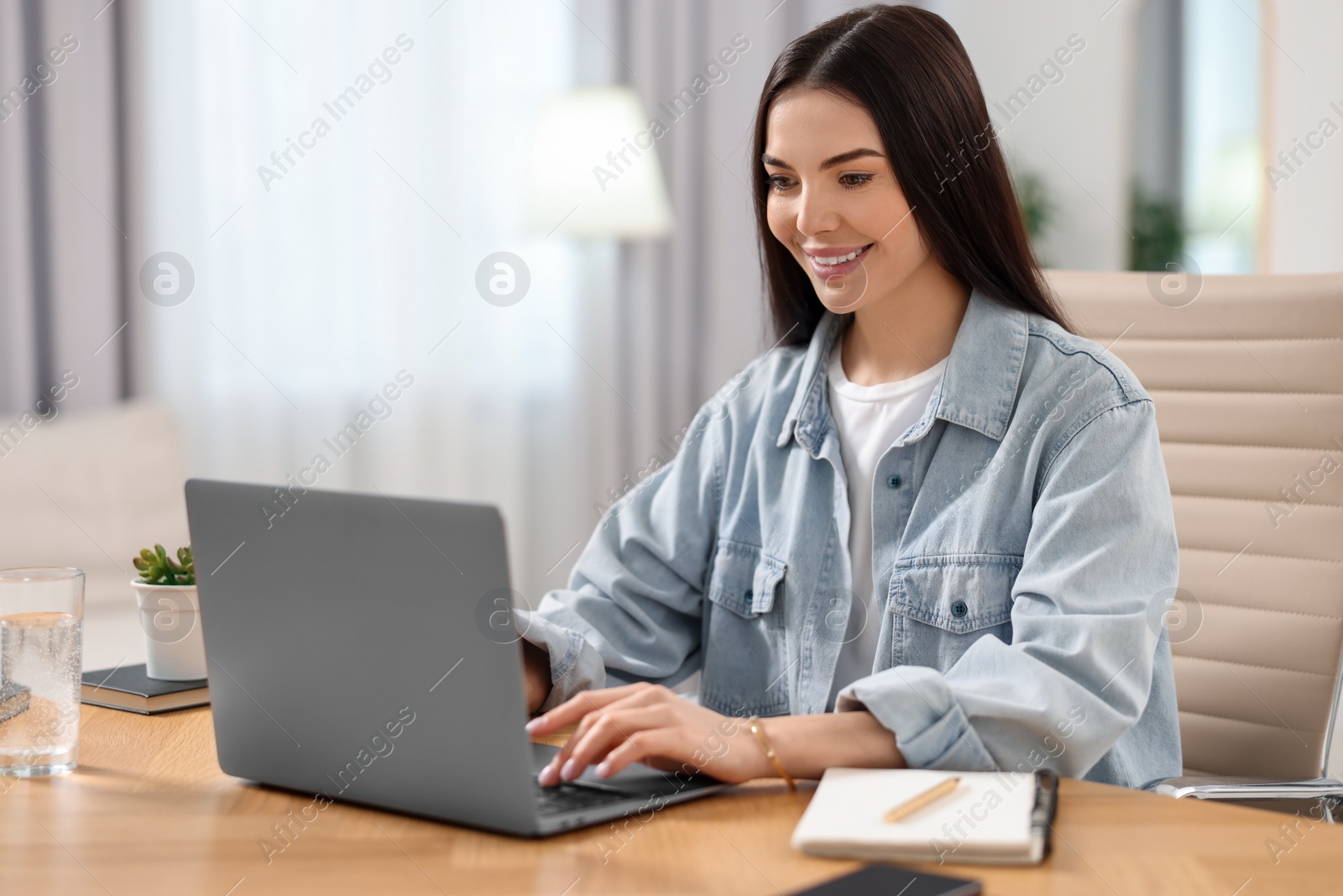 Photo of Young woman watching webinar at table in room