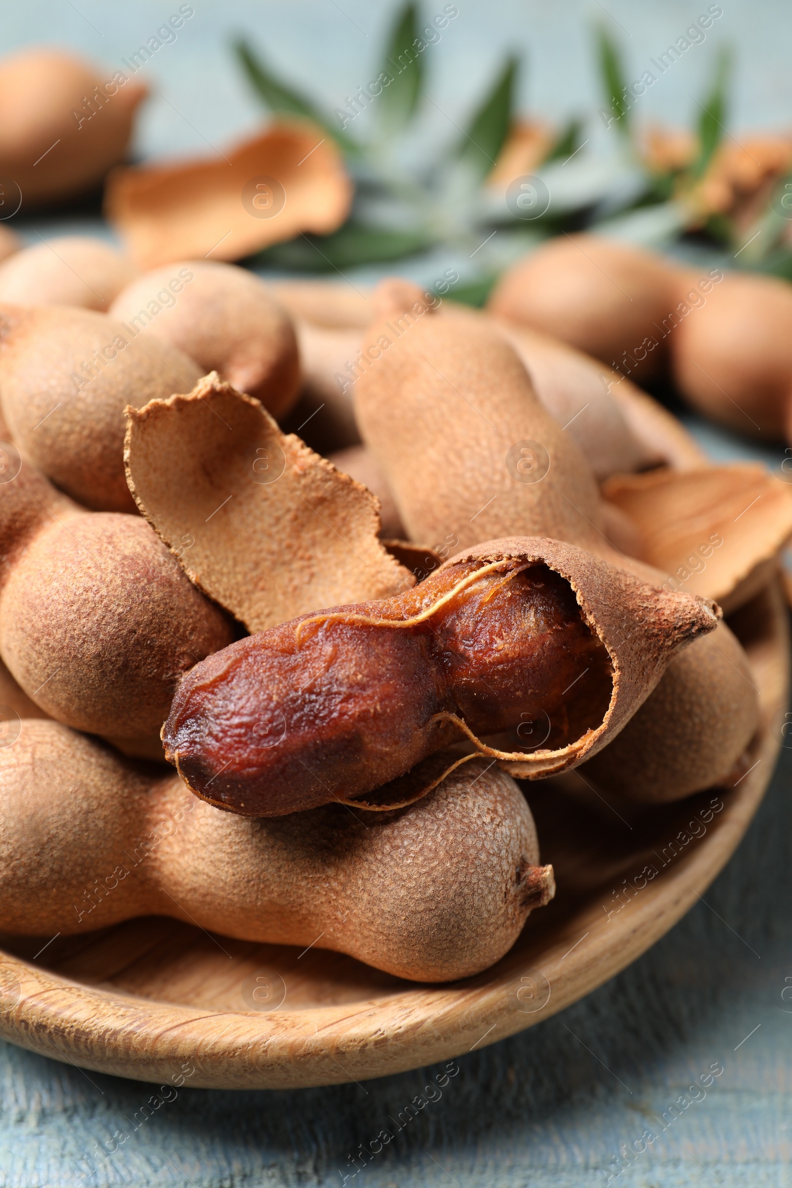 Photo of Plate with delicious ripe tamarinds on blue wooden table, closeup