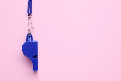 One blue whistle with cord on pink background, top view. Space for text