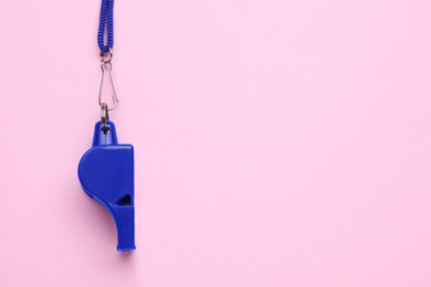 Photo of One blue whistle with cord on pink background, top view. Space for text