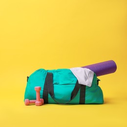 Photo of Blue gym bag and sports accessories on yellow background