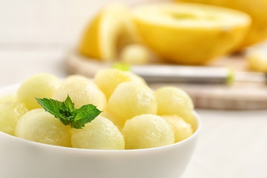 Photo of Bowl of melon balls with mint on table, closeup