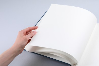Woman with open photo album at light table, closeup. Space for text