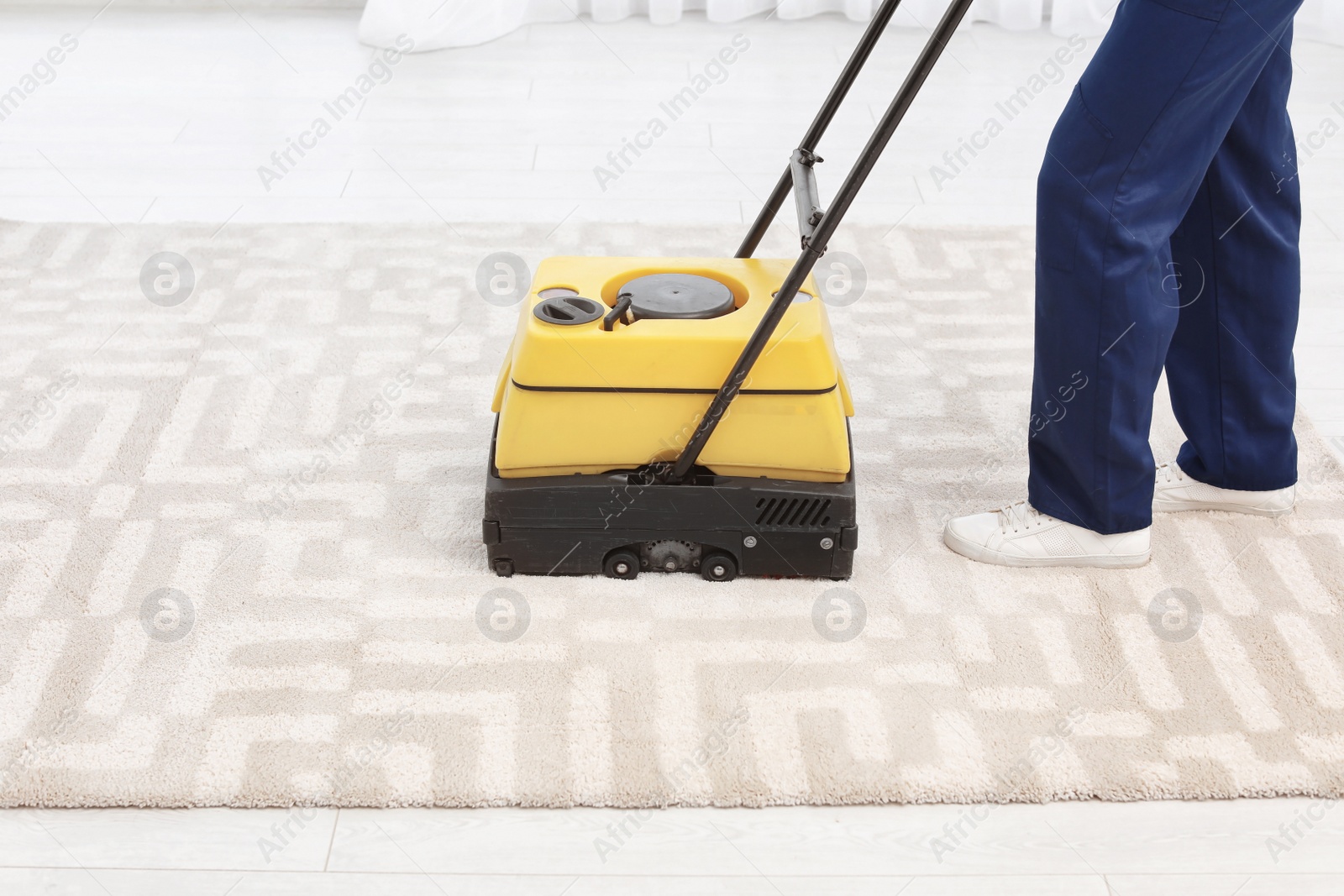 Photo of Male worker with carpet cleaner indoors, closeup