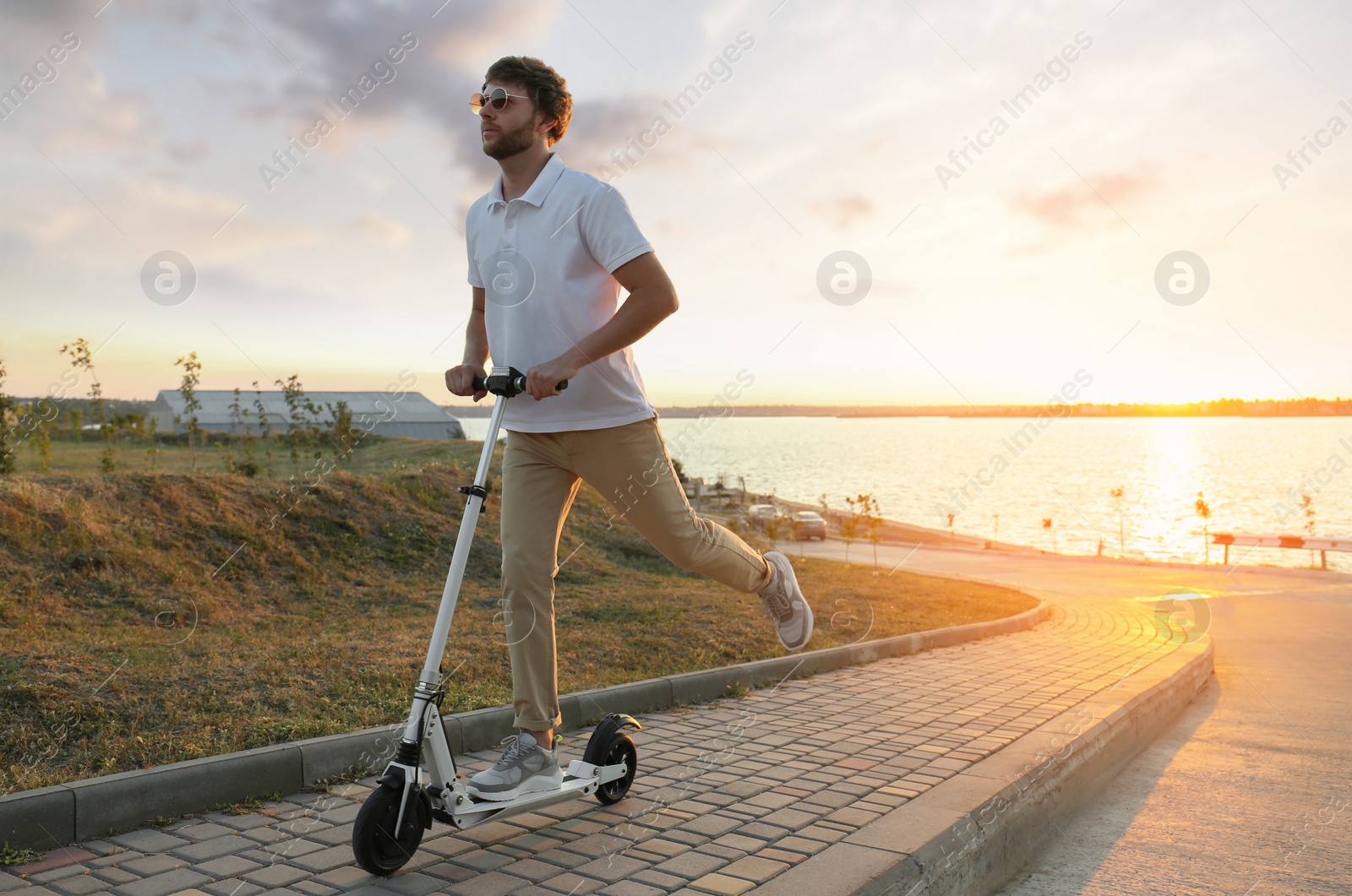 Photo of Man riding modern kick scooter along city street