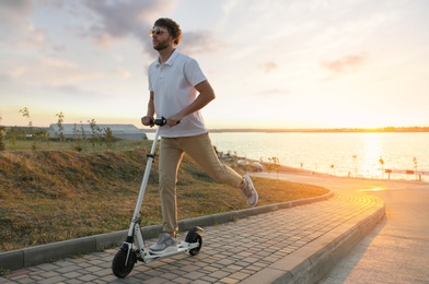 Photo of Man riding modern kick scooter along city street