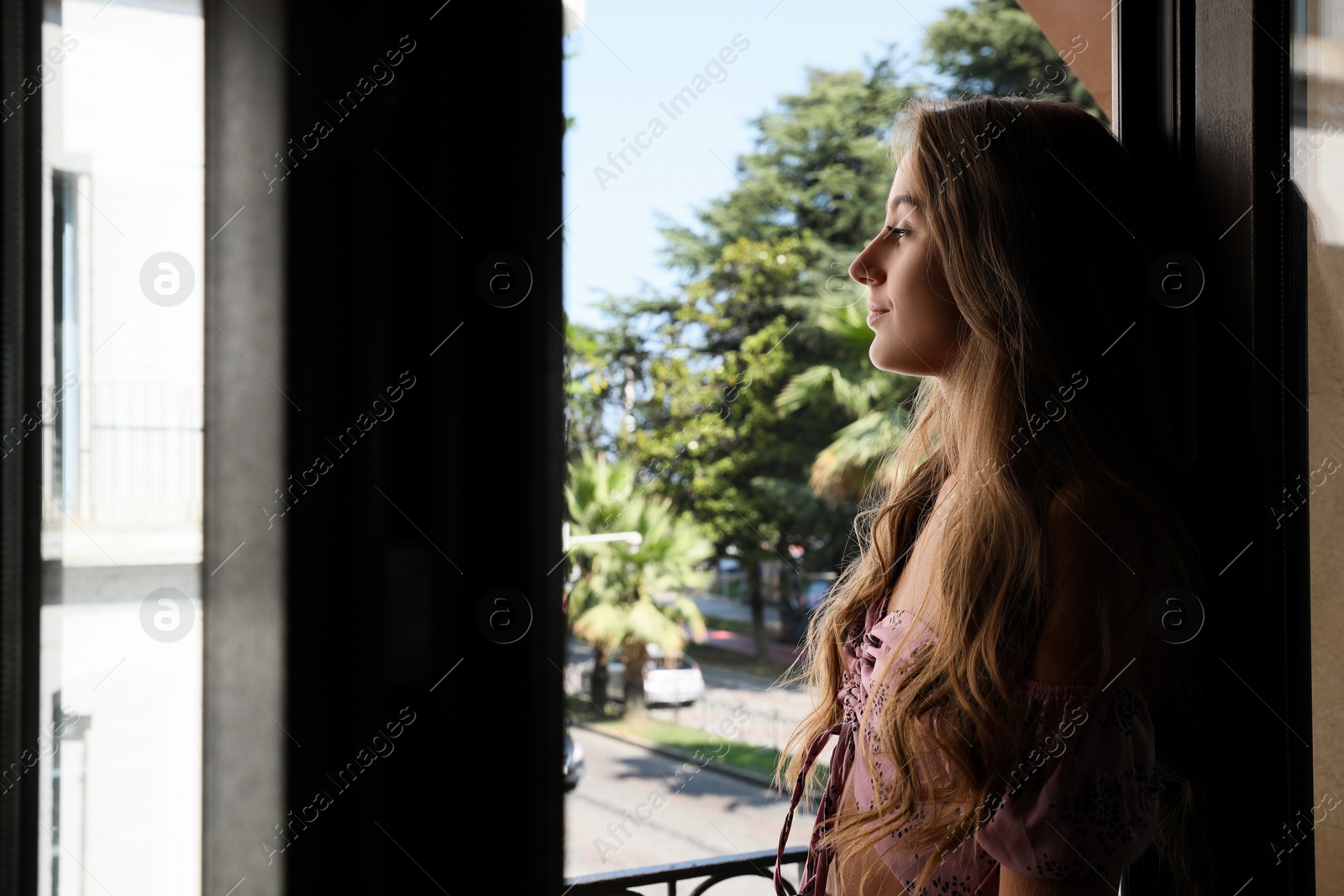 Photo of Beautiful young woman with long hair standing on balcony