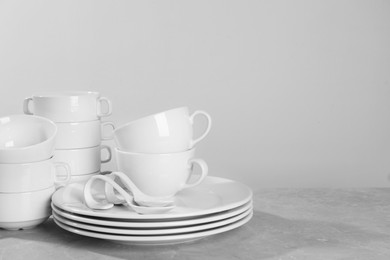 Set of clean dishware on grey table against light background. Space for text