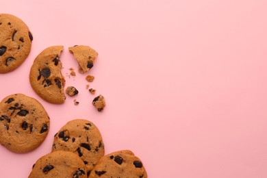 Photo of Many delicious chocolate chip cookies on pale pink background, flat lay. Space for text