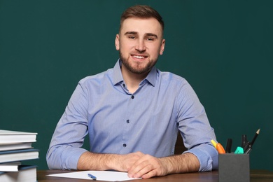 Photo of Portrait of young teacher at table against green background