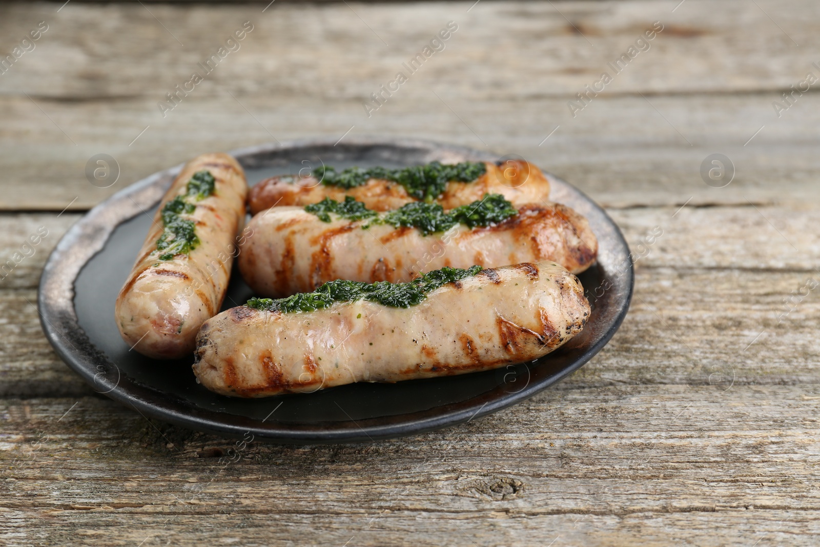 Photo of Tasty fresh grilled sausages with sauce on wooden table