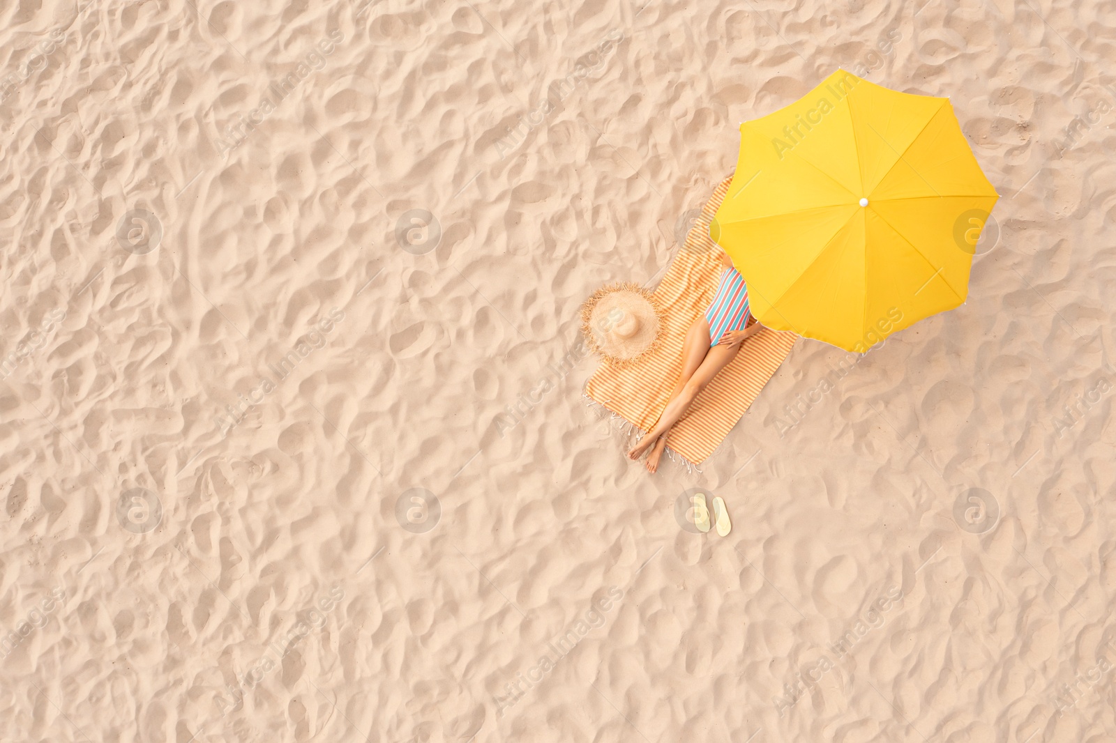 Image of Woman resting under yellow beach umbrella at sandy coast, aerial view. Space for text