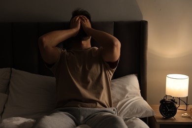 Man suffering from headache on bed at home