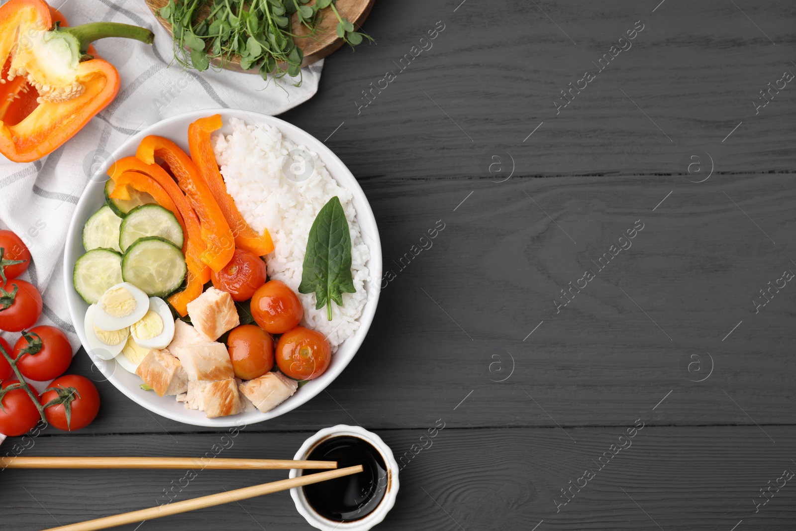 Photo of Delicious poke bowl with meat, rice, eggs and vegetables on black wooden table, flat lay. Space for text