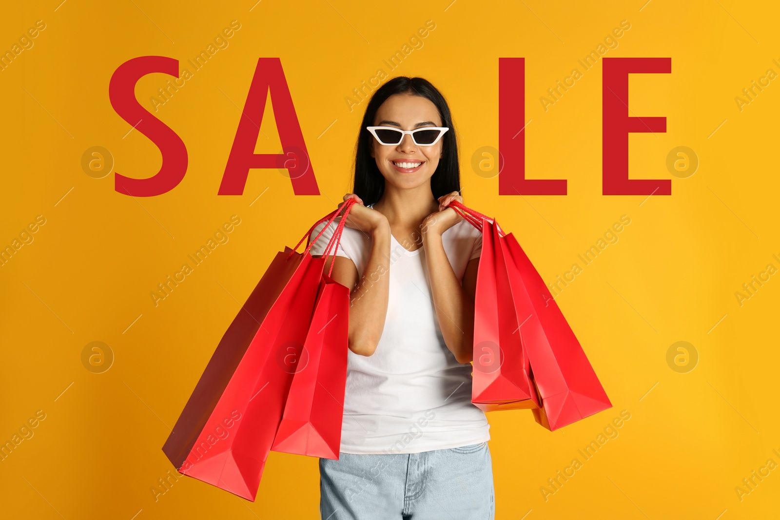 Image of Beautiful young woman with paper shopping bags and word SALE on yellow background