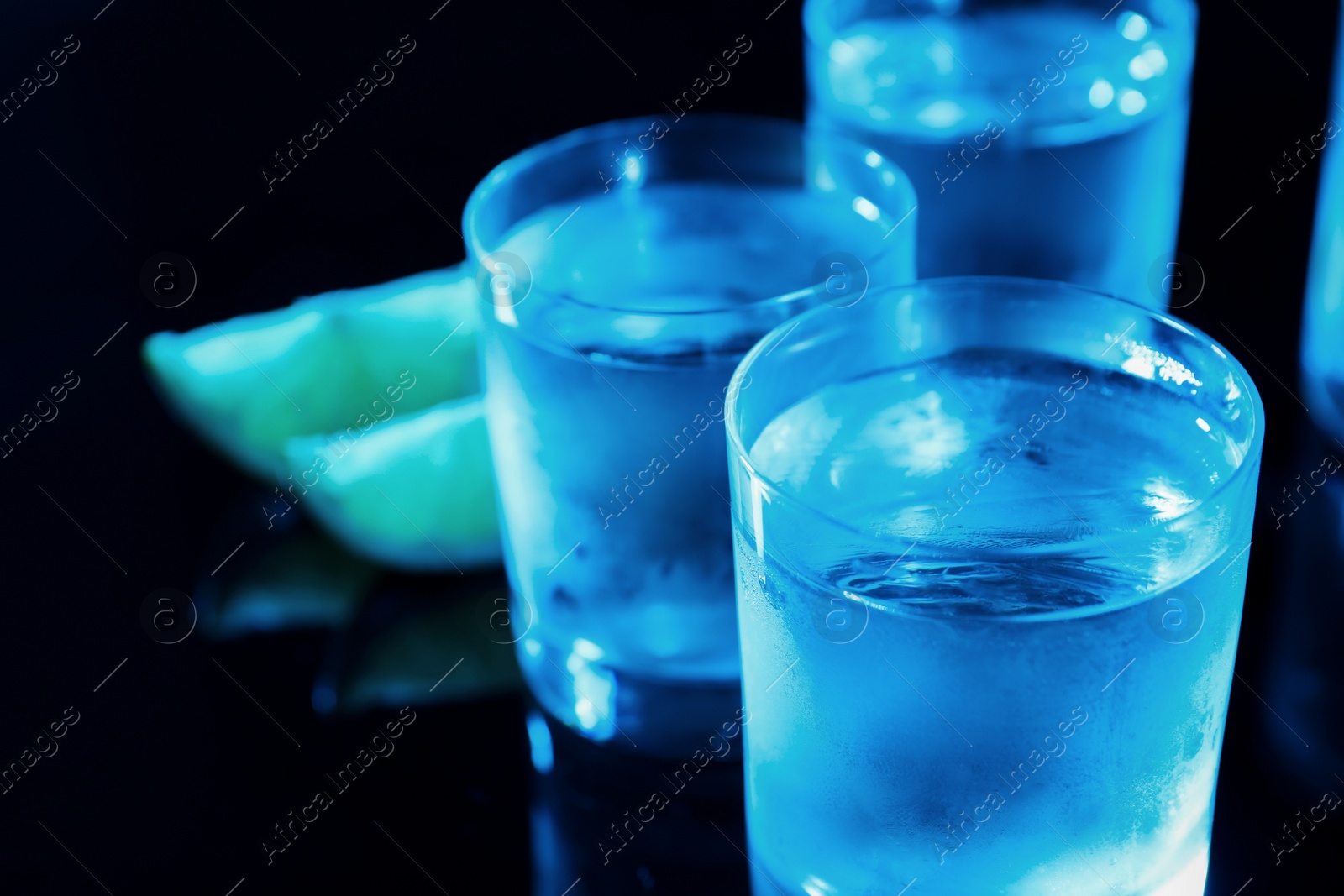 Photo of Shot glasses of vodka on dark background, closeup. Space for text