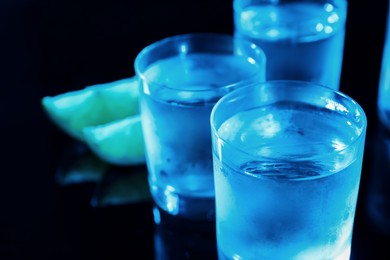 Photo of Shot glasses of vodka on dark background, closeup. Space for text