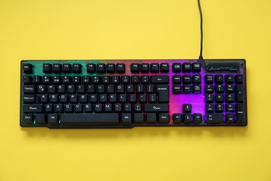 Photo of Modern RGB keyboard on yellow background, top view
