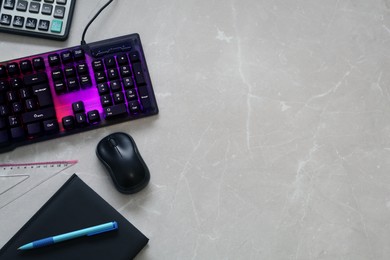 Photo of Modern RGB keyboard and stationery on light marble table, flat lay. Space for text