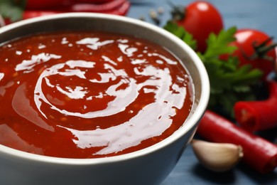 Photo of Spicy chili sauce in bowl on table, closeup