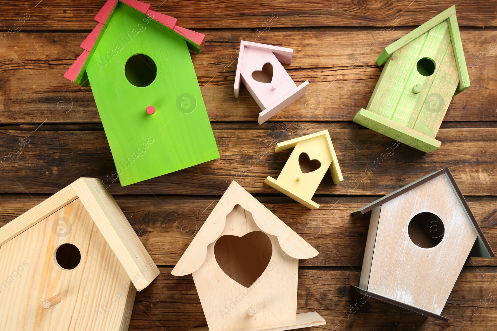 Photo of Many different bird houses on wooden background, flat lay