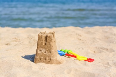 Photo of Sand castle and child plastic toys on beach near sea