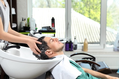 Photo of Stylist washing client's hair at sink in beauty salon