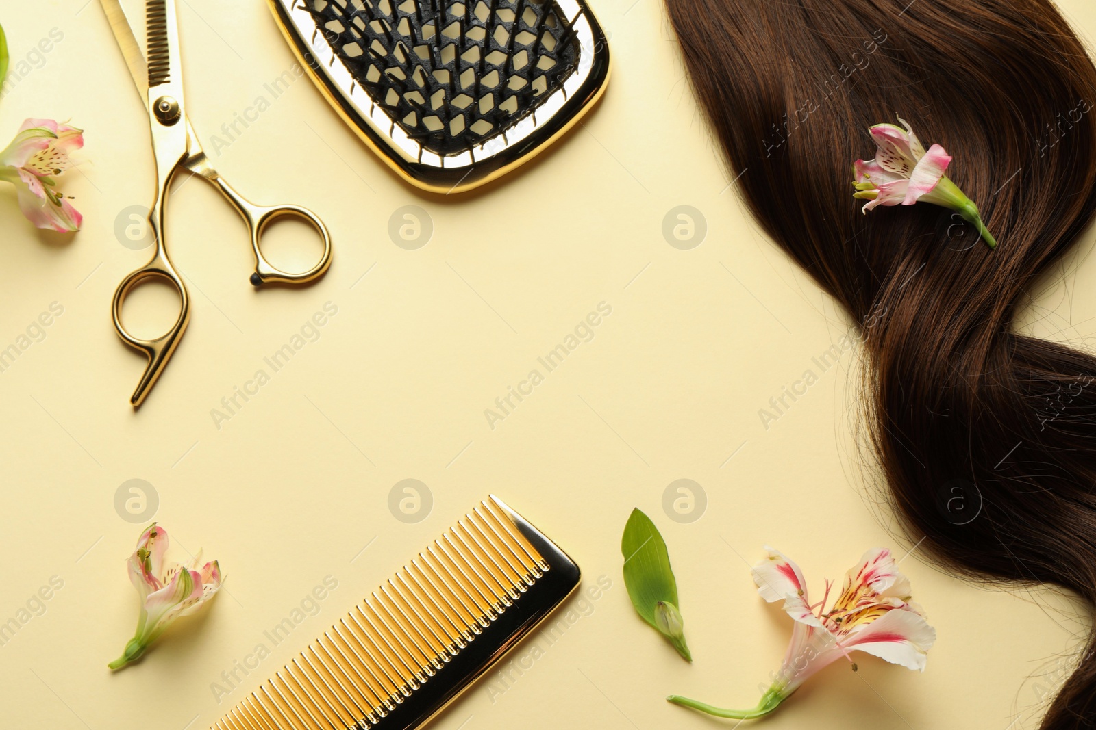 Photo of Flat lay composition with different hairdresser tools and flowers on pale yellow background, space for text