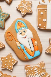 Photo of Tasty gingerbread cookies on white wooden table, flat lay. St. Nicholas Day celebration