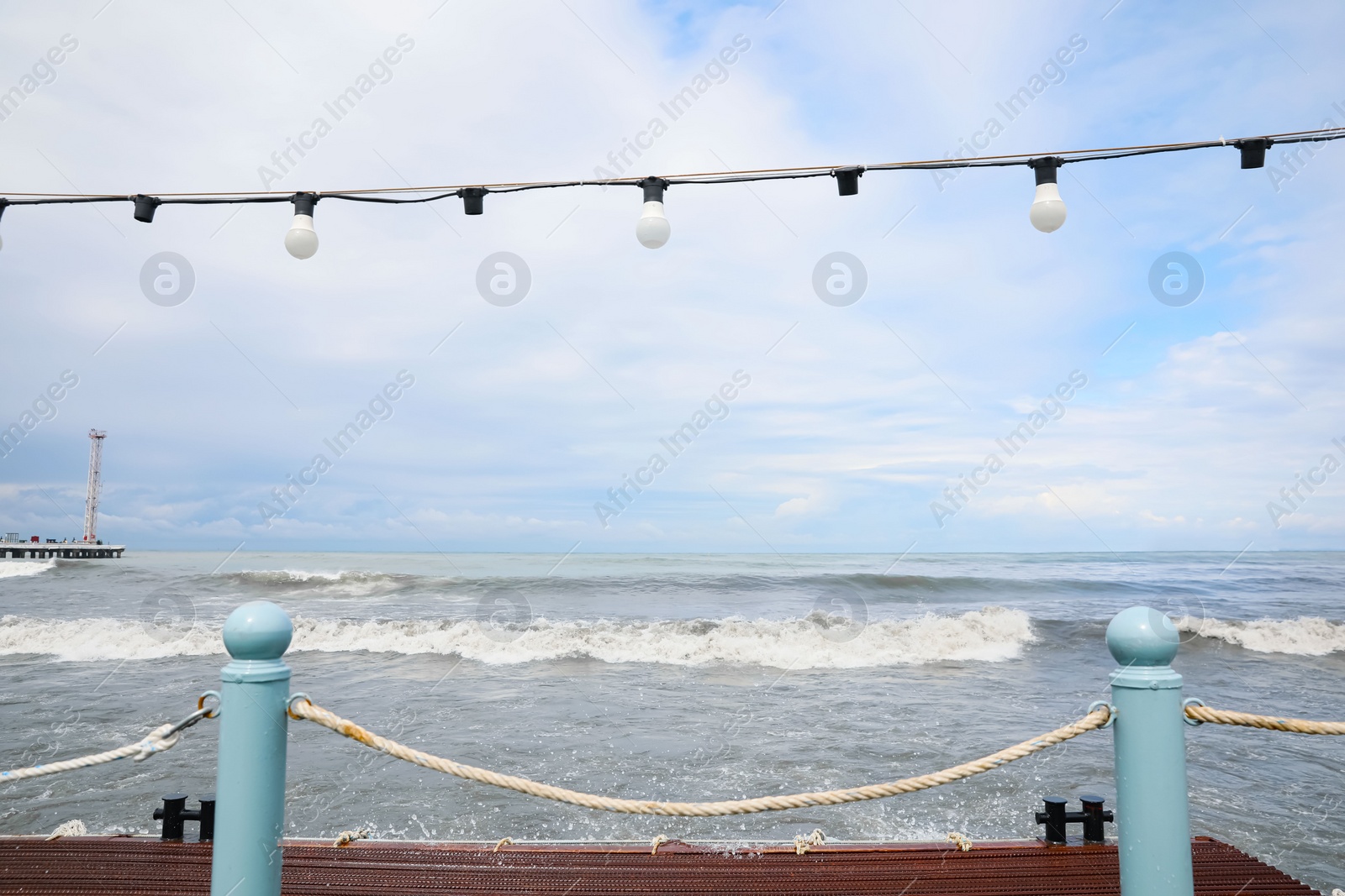 Photo of Picturesque view of sea with waves behind pier fence