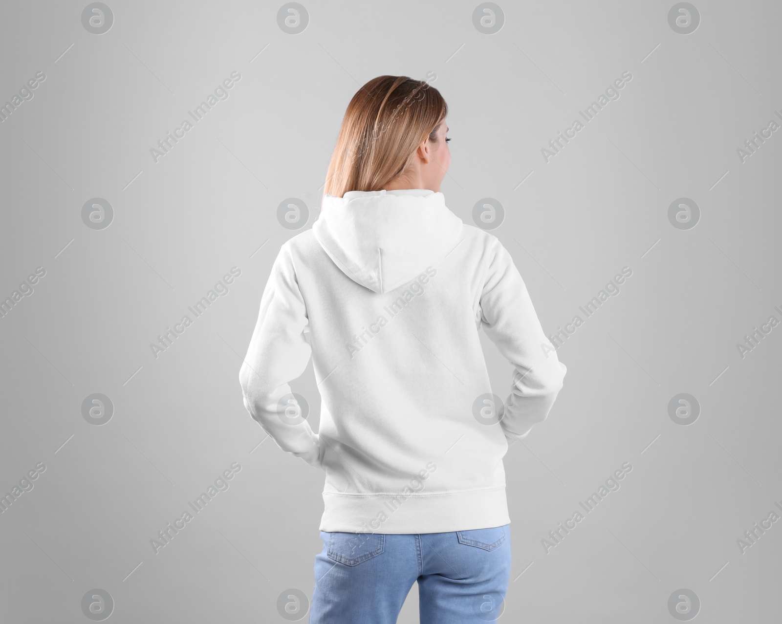 Photo of Woman in hoodie sweater on light background. Space for design