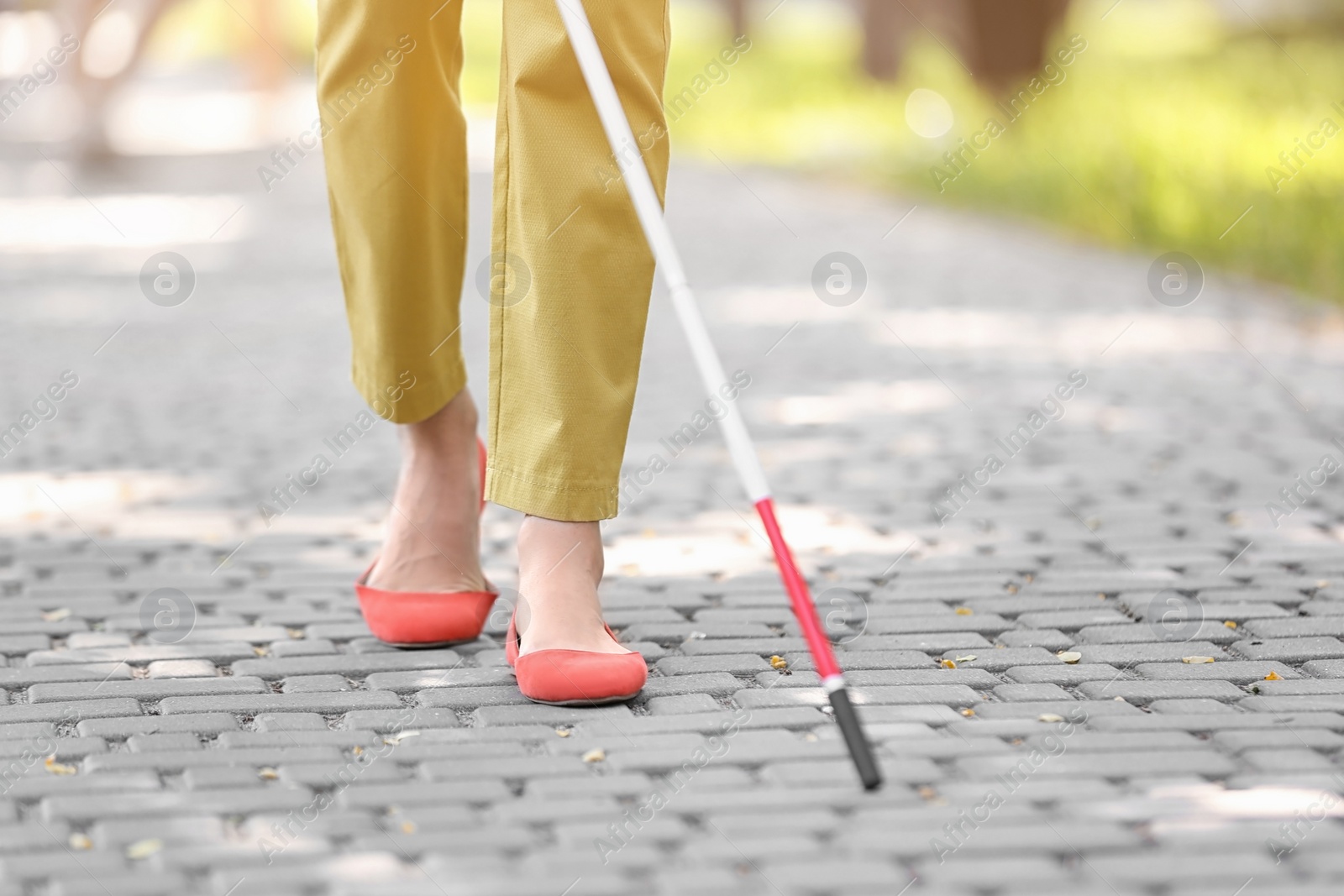 Photo of Blind woman with cane walking on city street, closeup