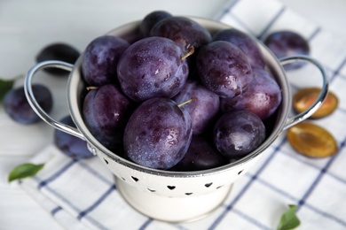 Photo of Delicious ripe plums in colander on table, closeup