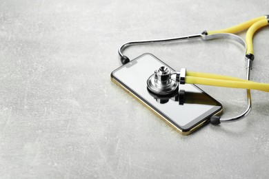 Stethoscope and modern smartphone on grey table. Space for text