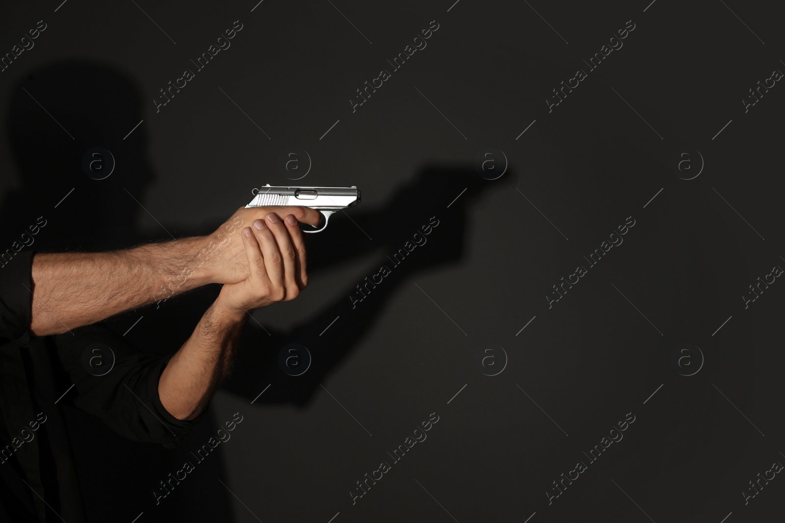 Photo of Professional killer with gun on black background, closeup