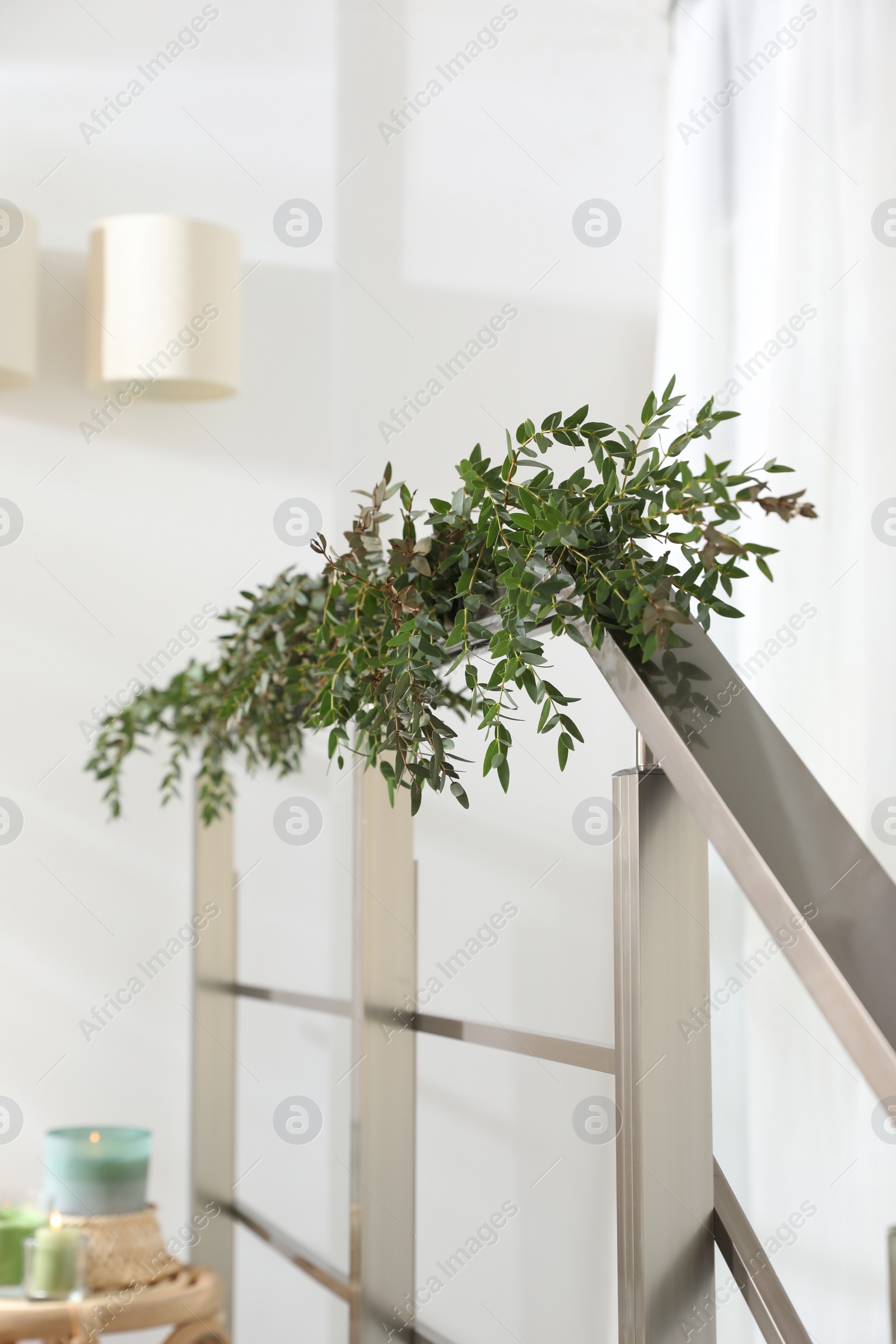 Photo of Beautiful garland made of eucalyptus branches on handrail indoors
