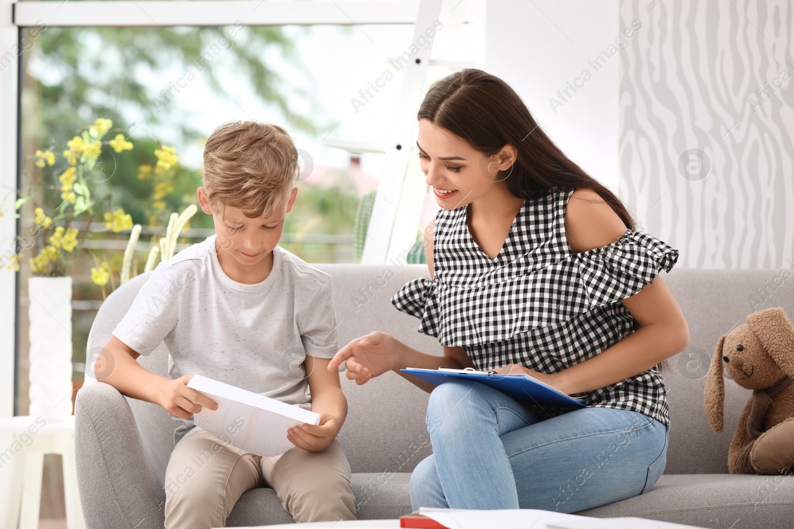 Photo of Young female psychologist working with little child in office