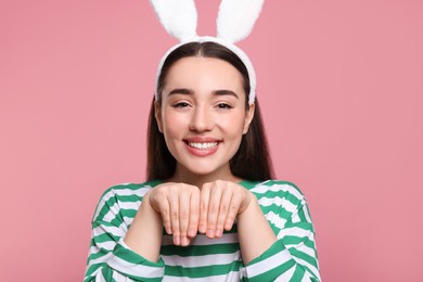 Photo of Happy woman wearing bunny ears headband on pink background. Easter celebration