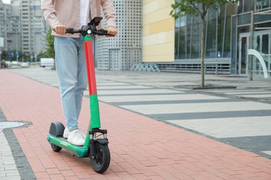 Photo of Man riding modern electric kick scooter on city street, closeup. Space for text